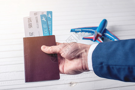 手持护照和白色背景的飞机票图片