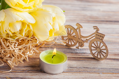 黄色郁金香和绿色点燃的蜡烛木制背景图片