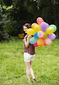 户外拿着五颜六色的气球的女孩图片