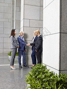 在现代办公大楼前厅与握手的多民族和多族裔商界人士会晤图片