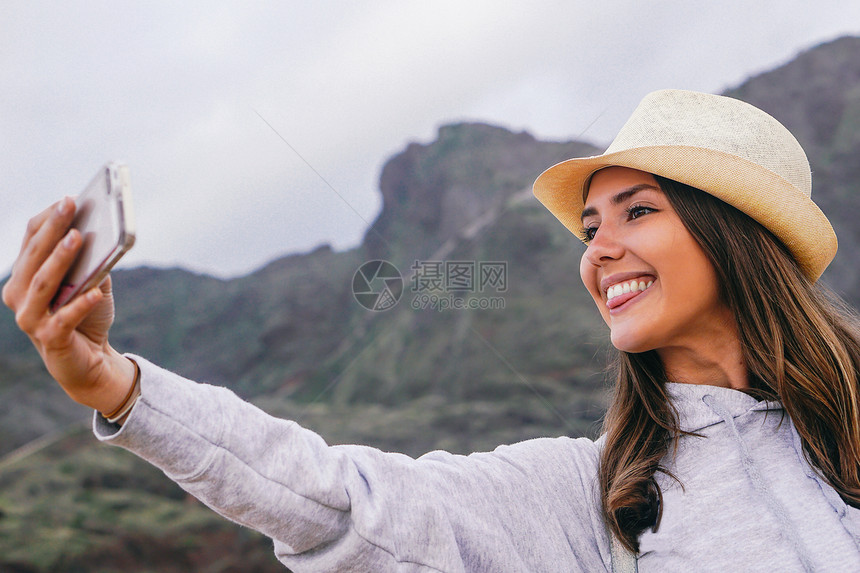 年轻漂亮的女人在度假时用她的移动智能手机相自拍图片