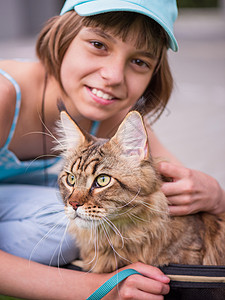 可爱的十岁孩子和她的猫一起玩皮带关闭图片