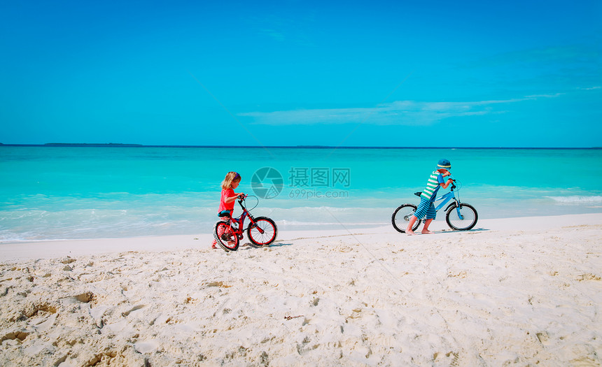 在热带海滩骑自行车的男女图片