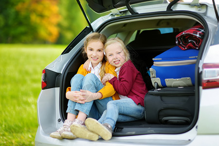 两个可爱的小女孩在和父母去度假前坐在车里图片