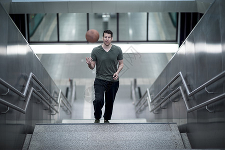 一个人手拿着篮球走在楼梯井上图片