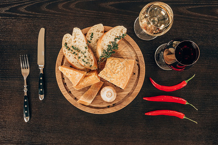 面包板木辣椒和桌上葡萄酒上加袋饼的图片