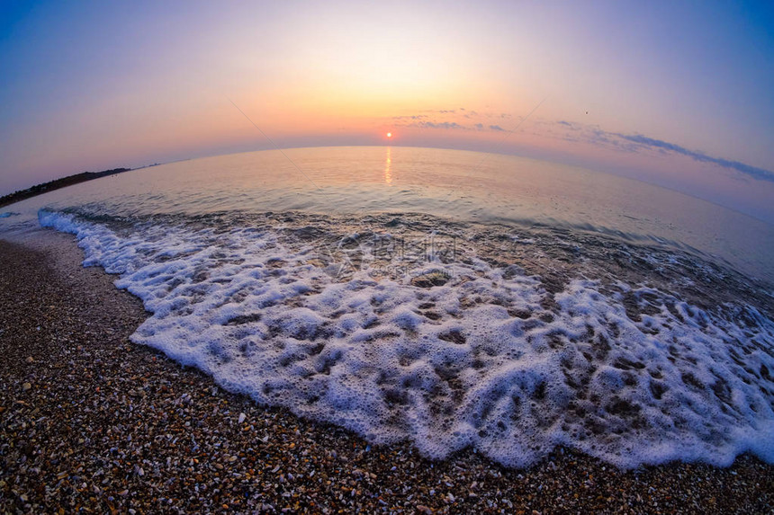 在沙滩上喷洒波浪的海面日出时图片
