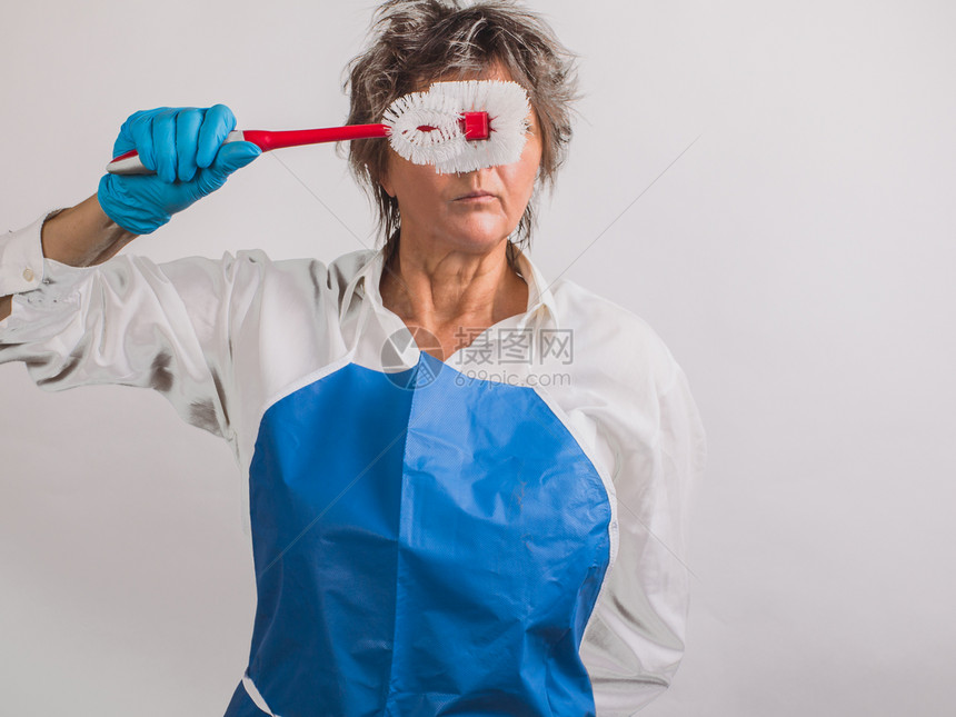 戴蓝色橡胶防护手套的高级严格女房屋清洁概图片