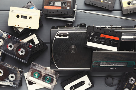 一堆复古的录音带和灰色背景的老式录音机老式媒体设备的顶视图复图片