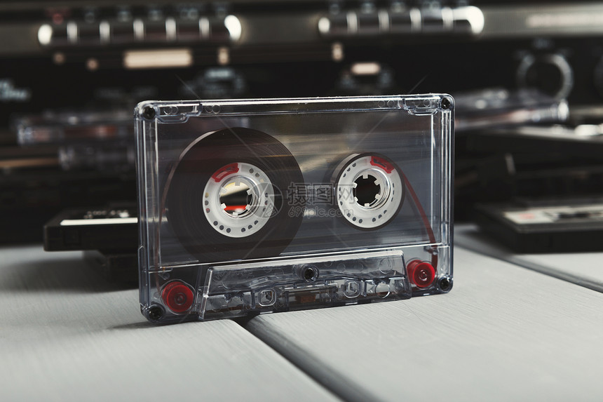 老式录音机前的复古录音带和灰色背景上的一堆磁带老式媒体设备的侧视图片