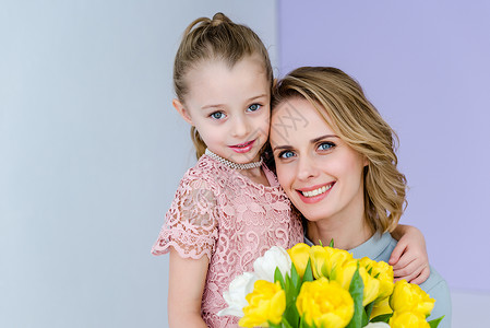 可爱的孩子拥抱母亲与郁金香花束图片