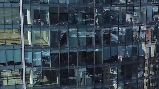 关闭现代摩天大楼的窗户云反映在现代办公楼缩放和平移天线反映晴朗蓝天的办公楼窗户前平背景图片