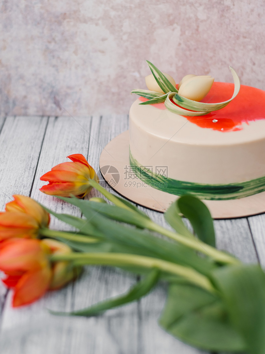 白色和红色装饰的蛋糕和红郁金花在木图片
