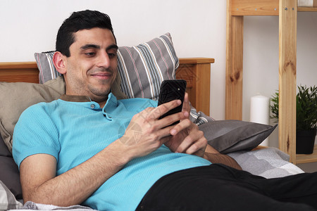 年轻快乐的阿拉伯男子使用智能手机图片