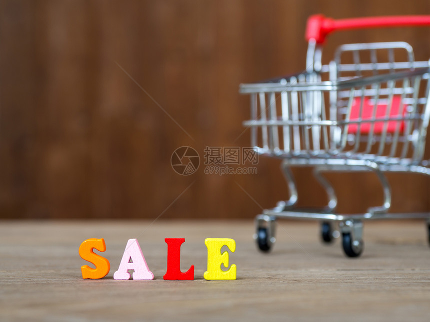 木桌和购物车和木制背景上的彩色木字销售由木字母颜色制成的英文字母购物和图片