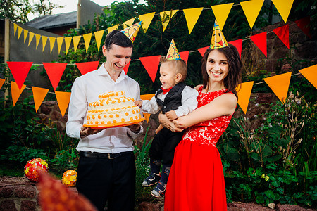 主题儿童的生日派对食物和糖果一个年轻的家庭庆祝儿子一周岁爸拿着一个大蛋糕背景