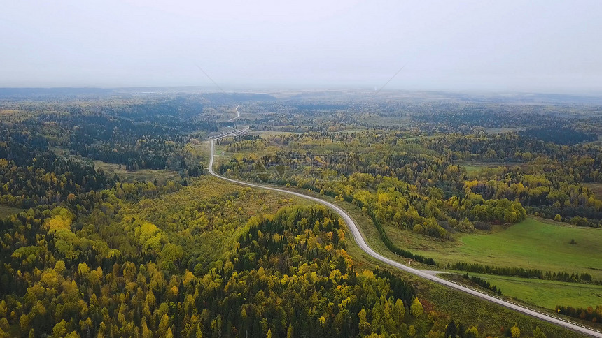 鸟瞰无限空间的森林平原和在高速公路上行驶的汽车夹子在秋季森林鸟瞰图的道路森林之间的道路图片