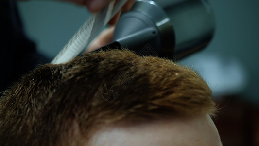 一个集中的棕色头发的商人在理发店梳理和修剪头发的特写镜头夹子理发师用图片