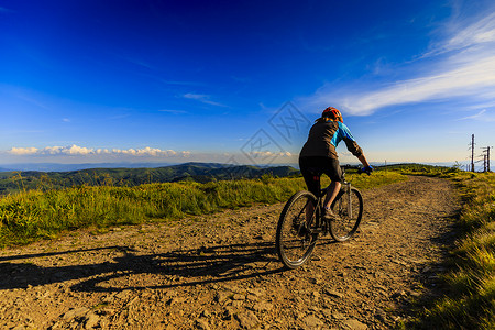 夏季山地森林景观日落时骑山地自行车骑自行车MTB流径的女人图片