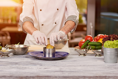 厨师在专业厨房做饭男厨师从不锈钢碗里拿出蔬菜厨师图片