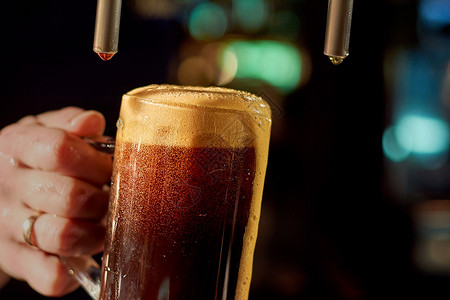 酒保手倒新鲜啤酒关闭酒保手在啤酒水龙头倒饮料在玻璃在啤酒图片