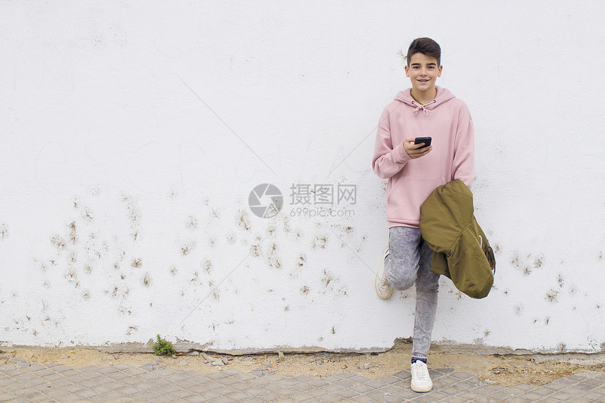 在市街墙上挂有手机的少年青图片