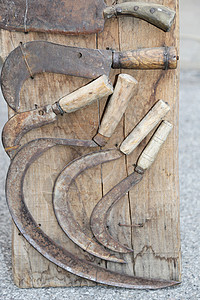 一套旧镰刀用来切割过去的干草或木头背景图片
