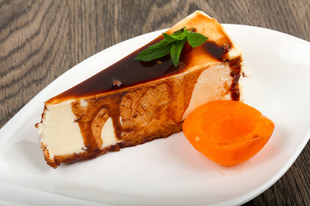 芝士蛋糕配巧克力和杏子在木制背景图片