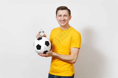 鼓舞人心的年轻快乐的欧洲男子球迷或穿着黄色制服的球员拿着足球背景图片