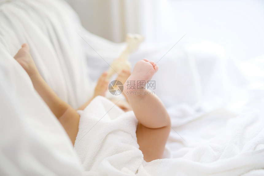 可爱的小宝洗澡后玩自己的脚可爱的漂亮女孩裹着白毛巾快乐健康的宝图片