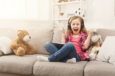 快乐兴奋的小女孩在平板电脑上玩在线游戏图片