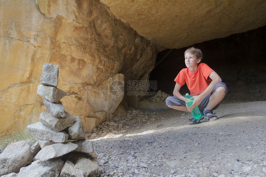 少年儿童从岩石洞穴看山景在露天前图片