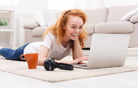 微笑的红发女学生一边用笔记本电脑一边学习图片