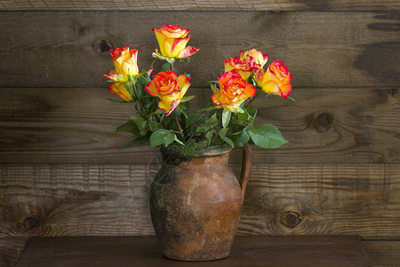 木制背景花瓶中的橙色玫瑰图片