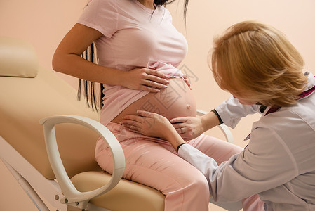 未来在医院的黑发妈和女医生抚摸她的肚子孕妇坐在医疗椅上图片