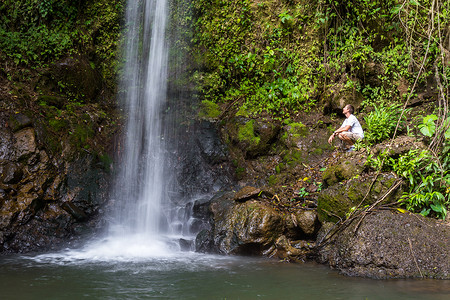 年轻男子站在哥斯达黎加雨林瀑布附近的一个图片