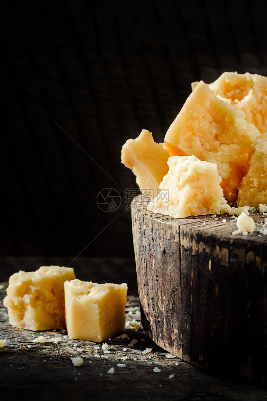 黑色背景的木制桌上的帕梅桑奶酪片段图片