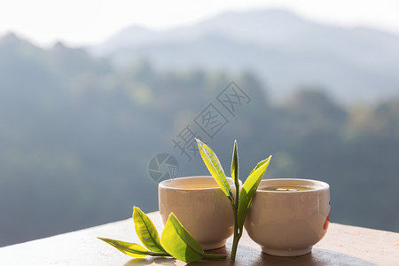 两杯茶叶放在桌子上山地风景阳光照耀图片