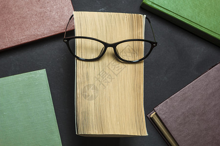 书本背景上的眼镜阅读学习的概图片