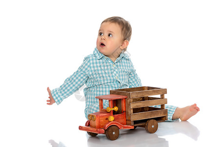 可爱的小男孩正在工作室里玩白色背景的玩具木车快乐童年家庭学习和教育图片