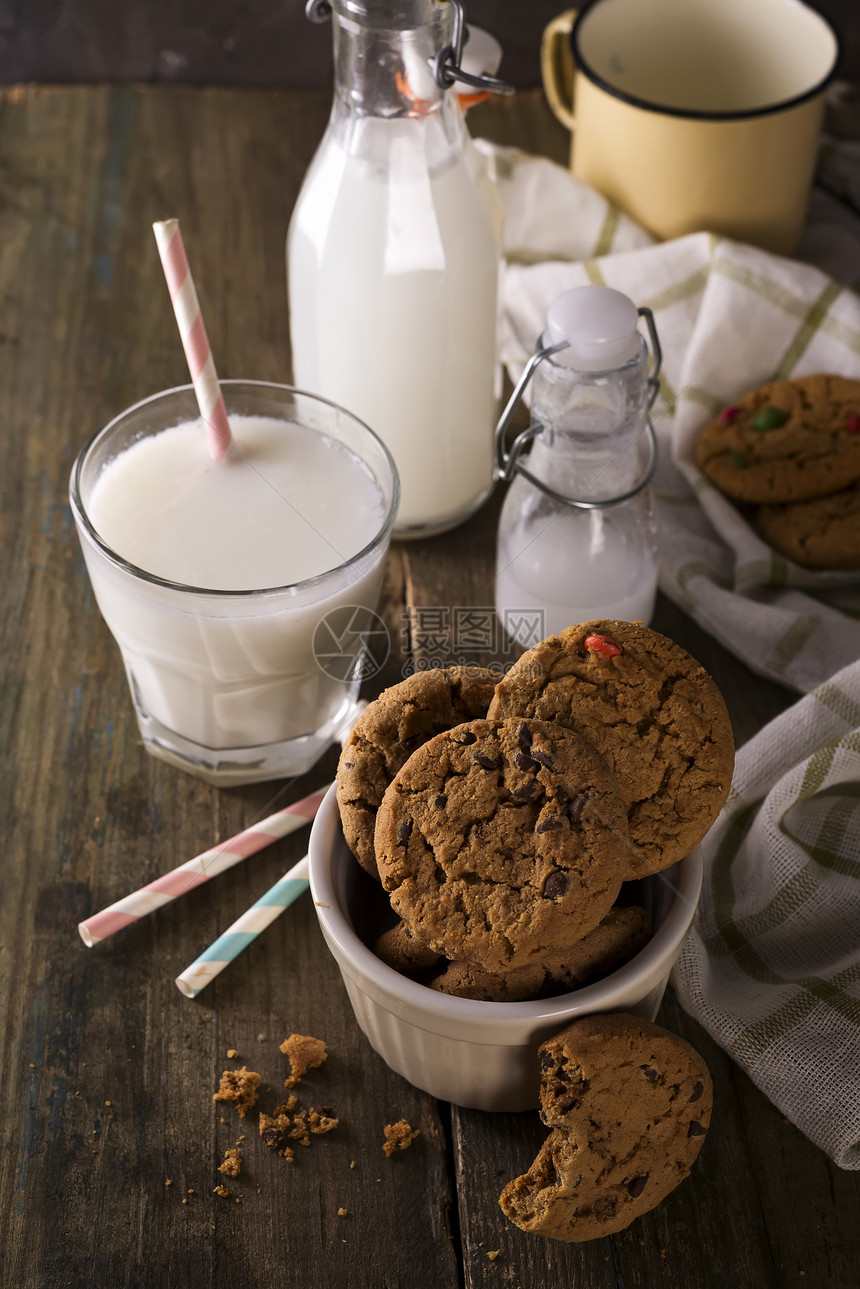 土制巧克力曲奇饼干和牛奶在生木背景图片