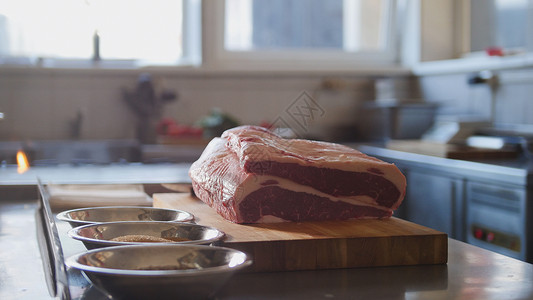 大块新鲜生肉躺在餐厅的木板上图片