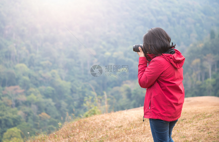 年轻女摄影师拍摄森林照片旅行概念图片