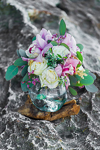 带有粉红兰花和玻璃锅中白玫瑰的彩虹花束图片