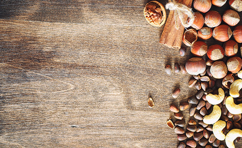 木桌上的不同坚果雪松腰果榛子核桃和桌子上的勺子许多坚果是带壳的图片