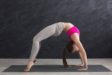 健身女人在灰色背景的健身房训练瑜伽在桌面姿势年轻苗条的女孩锻炼身图片