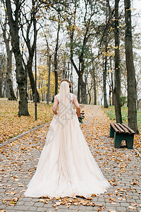 美丽的新娘在公园外露天手握着一束结婚花图片