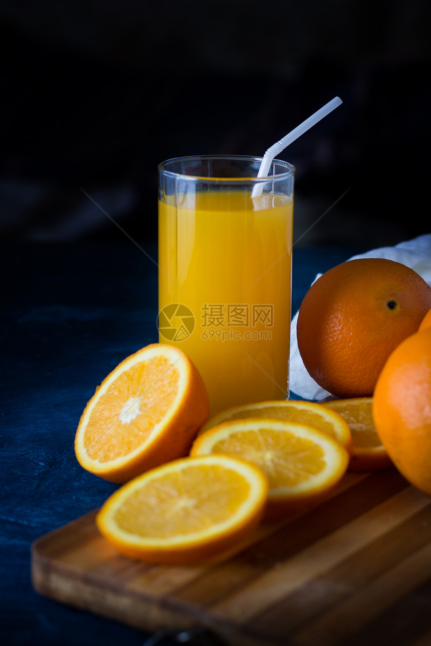 一杯带管子的新鲜橙汁木制餐桌橙片橙子深蓝色图片