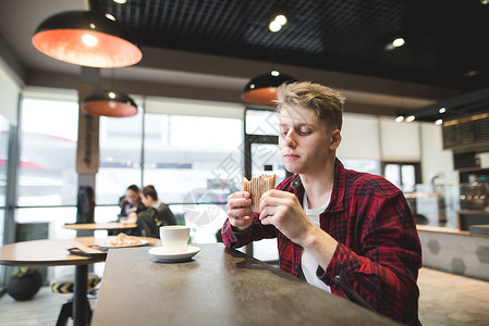 年轻学生在舒适的咖啡厅里用三明治和咖啡洗盘子图片