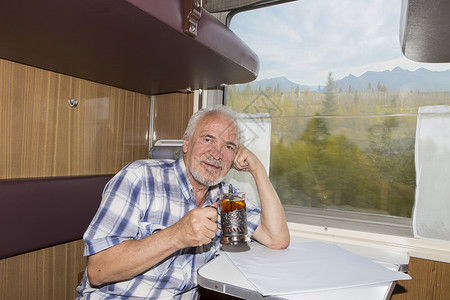 一位有魅力的老人在火车厢里喝茶图片